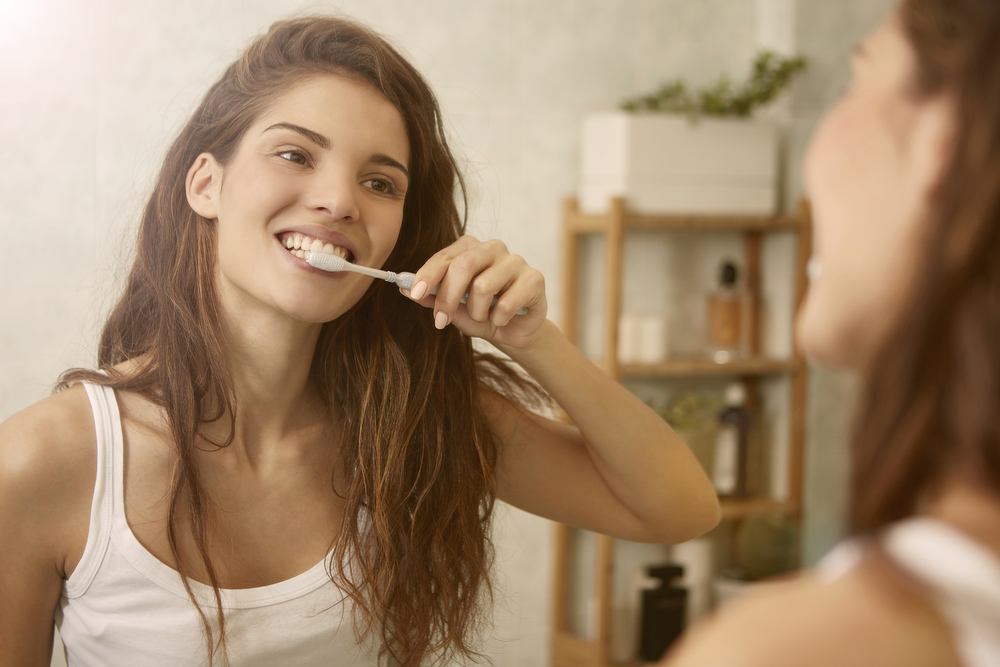 woman brushing teeth to improve oral health