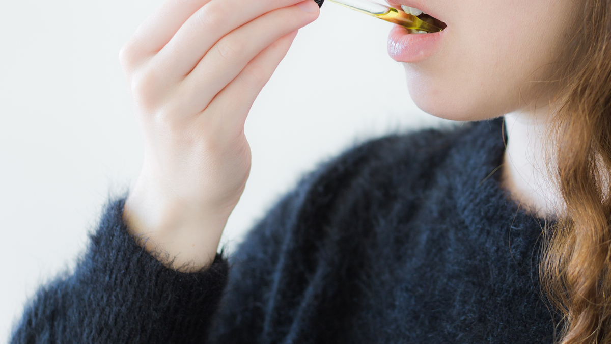 Woman taking CBD oil under her tongue