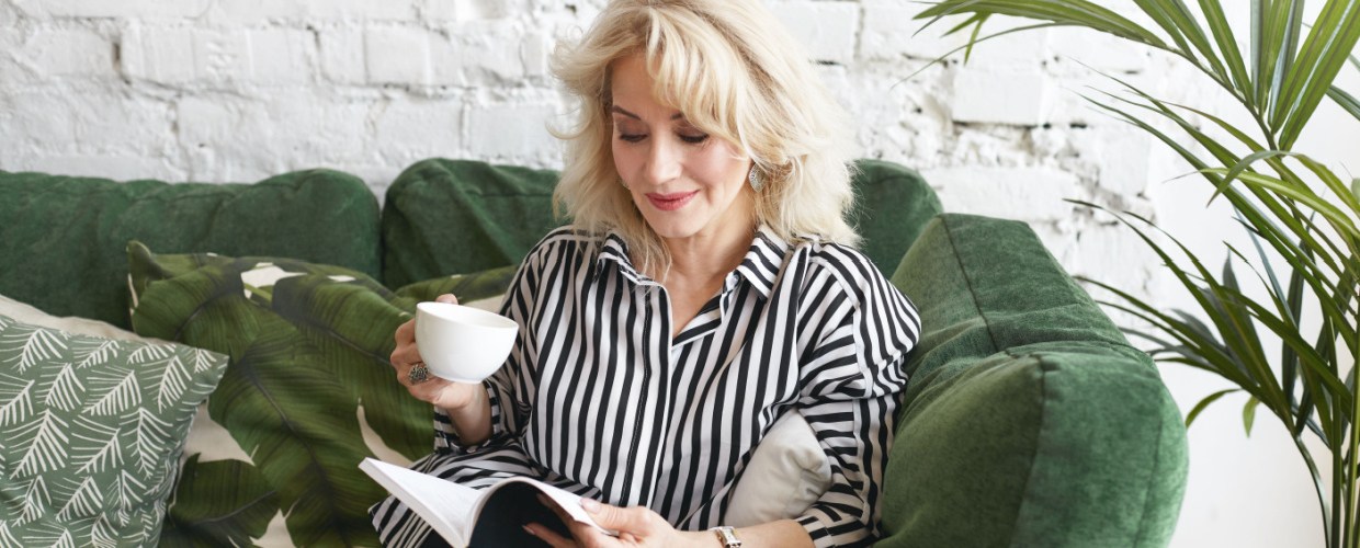 woman reading magazine sitting on sofa