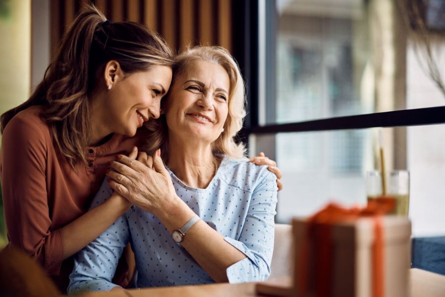 mother's day gifting concept, woman and mother embrace over gift