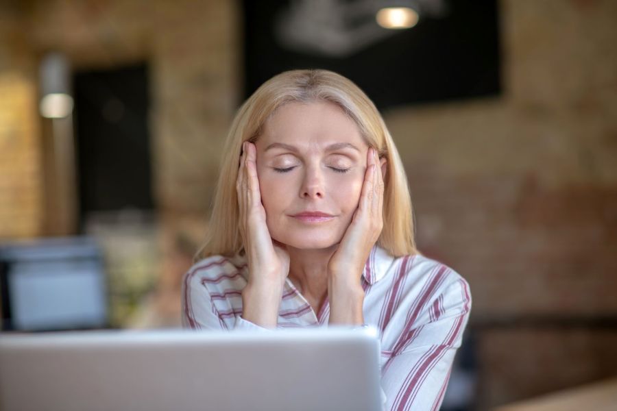 woman tired during the day in front of laptop experiencing menopause sleep problems during the night