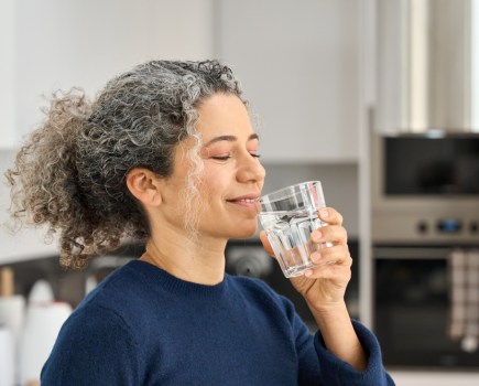 midlife woman drinking water taking supplements