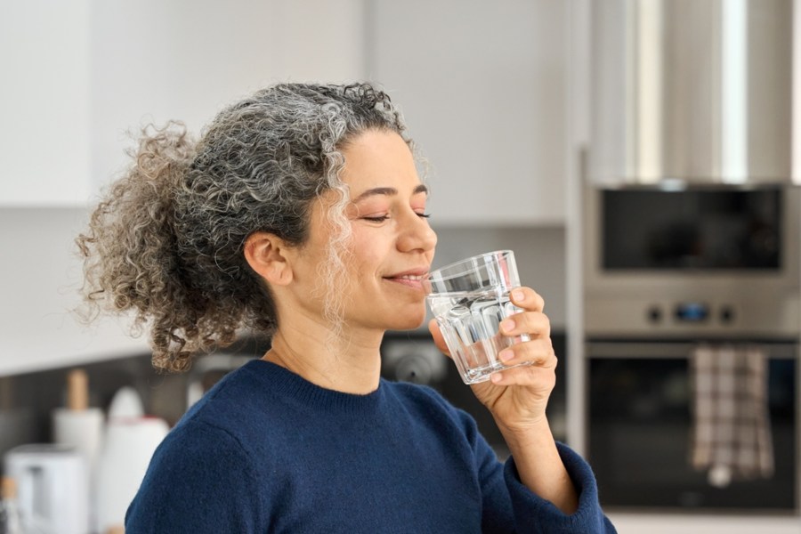 midlife woman drinking water taking supplements