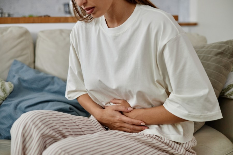A young woman holding her stomach in pain