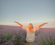 Back view of Middle-aged woman dressed boho style clothes, older female breath the healthy air in the field of lavender against the sun