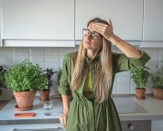Tired exhausted blonde woman feels headache touching head with closed eyes on kitchen at home. Unhealthy female in glasses suffers head pain, dizziness, migraine, cephalalgia feeling unwell pressure.