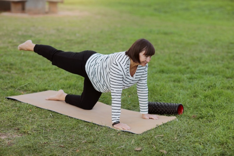 Mature woman doing Pilates on a mat in the park
