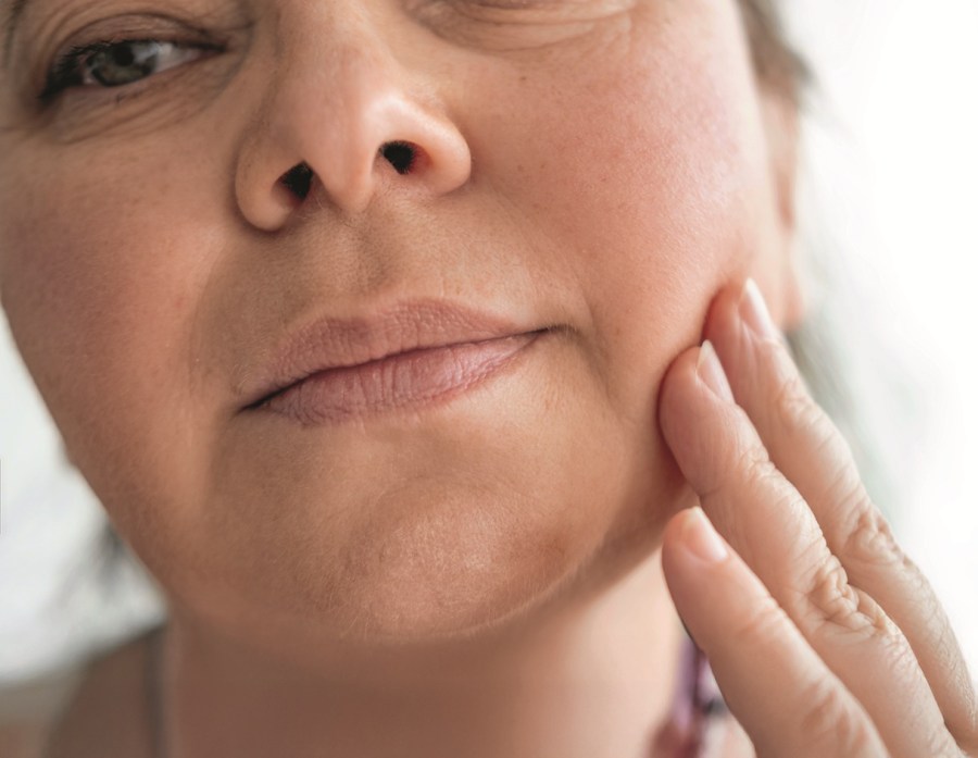mature woman gently touches face, accepting visible signs aging such wrinkles, sagging skin and changing facial shape with grace and self-love, self-discovery, self-acceptance ages